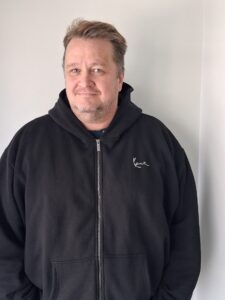 Kimmo Tiikkainen katsoo kameraan ja hymyilee.